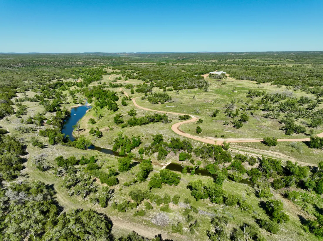 Cinematic aerial view of a lush green river valley in Texas hill country at dawn